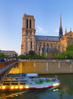 France, Paris, Notre Dame Cathedral and tour boat on River Seine at dusk France, Paris, Notre Dame Cathedral and tour boat on River Seine at dusk