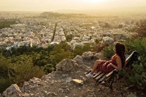 Girl seated on a bench at the Viewpoint of Athens at the lycabettus mount, Athens, Greece Girl seated on a bench at the Viewpoint of Athens at the lycabettus mount, Athens, Greece