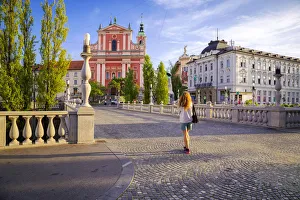 A girl walking in the old town of Ljubljana, with the Triple Bridge and the iconic A girl walking in the old town of Ljubljana, with the Triple Bridge and the iconic