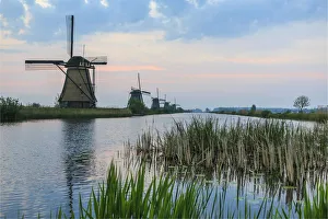 Green grass frames the windmills reflected in the canal at dawn Kinderdijk Rotterdam Green grass frames the windmills reflected in the canal at dawn Kinderdijk Rotterdam