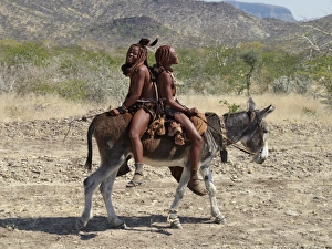 Two happy Himba girls ride a donkey to market Two happy Himba girls ride a donkey to market