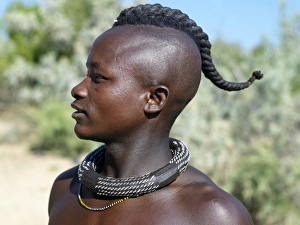 A Himba youth with his hair styled in a long plait, known as ondatu A Himba youth with his hair styled in a long plait, known as ondatu