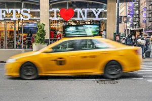 I Love New York gift shop sign and blurred yellow taxi cab passing, Times Square I Love New York gift shop sign and blurred yellow taxi cab passing, Times Square