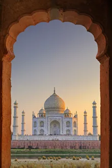 India, Taj Mahal at sunset framed by a temple arch India, Taj Mahal at sunset framed by a temple arch
