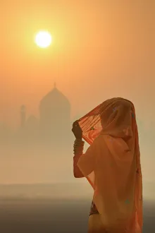 India, woman wearing a traditional sari on a foggy morning with the Taj Mahal in India, woman wearing a traditional sari on a foggy morning with the Taj Mahal in