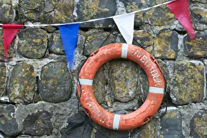Life ring and bunting on the old harbour wall at Clovelly, Devon, England. Summer Life ring and bunting on the old harbour wall at Clovelly, Devon, England. Summer
