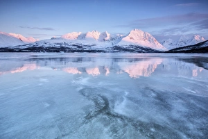 The last lights of dusk coloring the snowy Lyngen alps reflecting in the half frozen The last lights of dusk coloring the snowy Lyngen alps reflecting in the half frozen