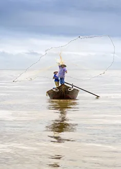 Local fisherman casting the fishing net from the boat, near Hoi An, Vietnam Local fisherman casting the fishing net from the boat, near Hoi An, Vietnam