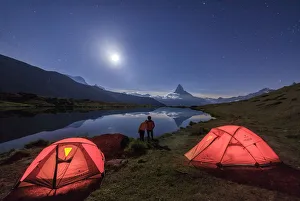 Lovers admire Matterhorn reflected in Lake Stellisee on a starry night of full moon Lovers admire Matterhorn reflected in Lake Stellisee on a starry night of full moon