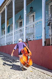 A man carrying a cello in Plaza Mayor in Trinidad, Sancti Spiritus, Cuba A man carrying a cello in Plaza Mayor in Trinidad, Sancti Spiritus, Cuba