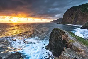 Madeira Island Prints: Man on cliffs looking at waves at dawn, Miradouro Do Guindaste viewpoint, Madeira island
