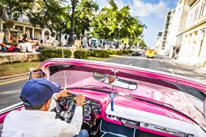 A man driving a classic car in Centro Habana District, Havana, Cuba A man driving a classic car in Centro Habana District, Havana, Cuba