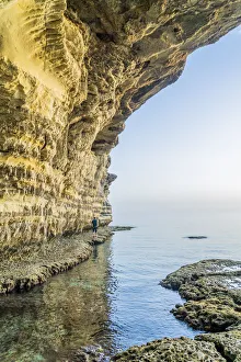 A man walking at the sea caves at Cape Greco, Famagusta District, Cyprus A man walking at the sea caves at Cape Greco, Famagusta District, Cyprus