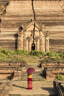 Mingun, Sagaing region, Myanmar (Burma). Woman with red umbrella looks at the Pahtodawgyi Mingun, Sagaing region, Myanmar (Burma). Woman with red umbrella looks at the Pahtodawgyi