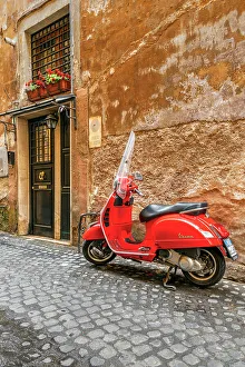 Parked red Vespa scooter in a cobbled street of Rome, Lazio, Italy Parked red Vespa scooter in a cobbled street of Rome, Lazio, Italy