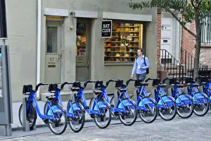 Pedestrian walking past a rack of Citi Bikes on Spring street, in Soho, Manhattan Pedestrian walking past a rack of Citi Bikes on Spring street, in Soho, Manhattan