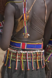 A Pokot woman in traditional attire with patterned cicatrices on her back attends an A Pokot woman in traditional attire with patterned cicatrices on her back attends an