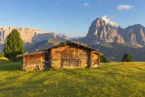 Last rays of sun on traditional hut with view on Sassolungo and Sella Group Last rays of sun on traditional hut with view on Sassolungo and Sella Group