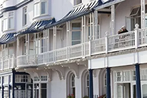 Retired couple sat on balcony, Regency houses, Sidmouth, Devon, UK Retired couple sat on balcony, Regency houses, Sidmouth, Devon, UK