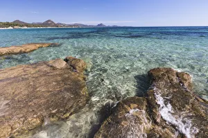 Rocks frame the turquoise water of sea around the sandy beach of Sant Elmo Castiadas Rocks frame the turquoise water of sea around the sandy beach of Sant Elmo Castiadas