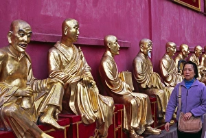 A row of golden Buddha statues greets visitors to the A row of golden Buddha statues greets visitors to the
