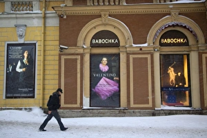 Russia, St. Petersburg; A man walking in front of high end clothes adverts in the city centre in Winter Russia, St. Petersburg; A man walking in front of high end clothes adverts in the city centre in Winter