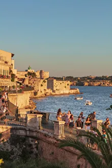 Siracusa, Sicily. People walking by the sea at sunset
