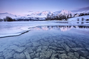 Snowy peaks are reflected in the frozen Lake Jaegervatnet at sunset Stortind Lyngen Snowy peaks are reflected in the frozen Lake Jaegervatnet at sunset Stortind Lyngen