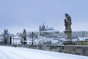 Statues at snow-covered Charles bridge and Prague Castle in winter, Prague, Bohemia Statues at snow-covered Charles bridge and Prague Castle in winter, Prague, Bohemia