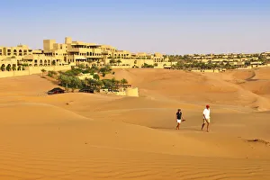 Tourists wander through dunes outside the desert luxury hotel Anantara Qasr Al Sarab Tourists wander through dunes outside the desert luxury hotel Anantara Qasr Al Sarab