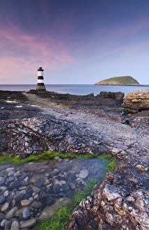 Twilight on the rocky Anglesey coast looking towards Penmon Point Lighthouse and Puffin Island Twilight on the rocky Anglesey coast looking towards Penmon Point Lighthouse and Puffin Island