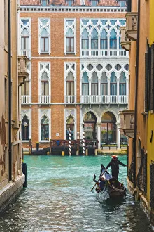 Waterfront palaces and tourists on gondola in a narrow canal tributary of the Grand Canal Waterfront palaces and tourists on gondola in a narrow canal tributary of the Grand Canal