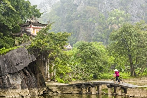 Woman crossing bridge with bicycle to temple, Tam Coc nr Ninh Binh, nr Hanoi, Vietnam Woman crossing bridge with bicycle to temple, Tam Coc nr Ninh Binh, nr Hanoi, Vietnam