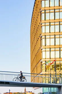 A woman riding a bike on a suspended bridge in Copenhagen at sunset, Denmark A woman riding a bike on a suspended bridge in Copenhagen at sunset, Denmark