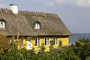 A yellow thatched cottage on the coast near Skodsborg, Zealand, Denmark A yellow thatched cottage on the coast near Skodsborg, Zealand, Denmark