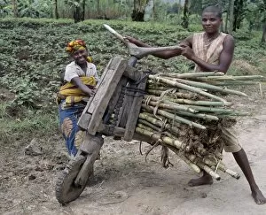 Related Images Collection: A young man and his wife push a homemade wooden bicycle