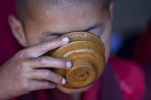 A young monk drinking milk from a wooden bowl in Bhutan A young monk drinking milk from a wooden bowl in Bhutan