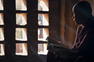 Southeast Asian Spirituality Prints: A young monk looking out of a window while studying inside a temple, UNESCO, Bagan