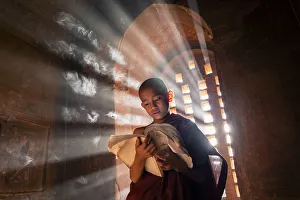 Print of a young monk reading by a temple window in Bagan, Myanmar