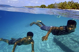 Over under image of marshallese boys smiling underwater Over under image of marshallese boys smiling underwater