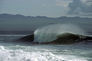 Spume and spindrift from a breaking wave with Santa Cruz Island in background. North Seymour Island, Galapagos Islands Spume and spindrift from a breaking wave with Santa Cruz Island in background. North Seymour Island, Galapagos Islands