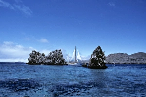 Yacht Aspasia Alpha sailing past Devils Crown, off Punta Cormorant. Floreana Island, Galapagos, Ecuador Yacht Aspasia Alpha sailing past Devils Crown, off Punta Cormorant. Floreana Island, Galapagos, Ecuador