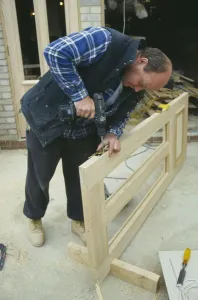 Building Architecture Design Prints: ARCHITECTURE Construction Carpentry Carpenter using power screwdriver to secure hinge to door