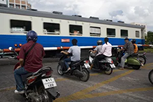 People on scooters at level crossing waiting train to pass People on scooters at level crossing waiting train to pass
