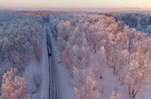 Russia Collection: An aerial view shows a car driving along a forest road during sunset in the Siberian