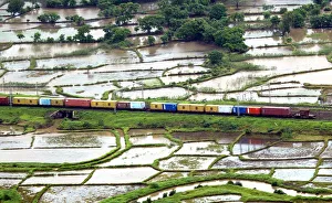 An aerial view of a train passing through a track surrounded by vast expanse of farmlands An aerial view of a train passing through a track surrounded by vast expanse of farmlands