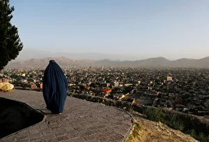 An Afghan woman walks on a hilltop overlooking Kabul, Afghanistan An Afghan woman walks on a hilltop overlooking Kabul, Afghanistan