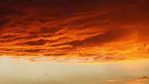 An airplane flies under a cloud formation at sunset in Los Angeles An airplane flies under a cloud formation at sunset in Los Angeles