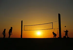 Beachgoers play volleyball at the beach as the sun sets in Carlsbad, California Beachgoers play volleyball at the beach as the sun sets in Carlsbad, California