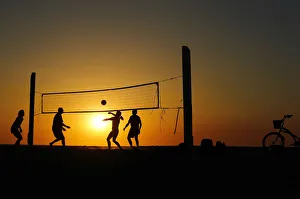 Beachgoers play volleyball at the beach as the sun sets in Carlsbad, California Beachgoers play volleyball at the beach as the sun sets in Carlsbad, California